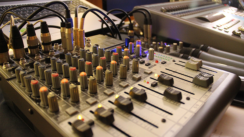 Foto de um equipamento de áudio com diversos botões e cabos conectados.