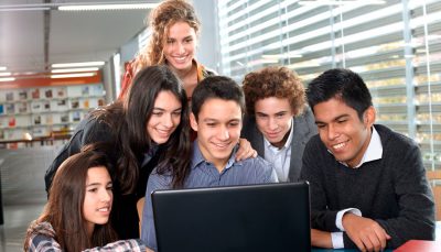 Grupo de seis jovens olhando para tela de um computador