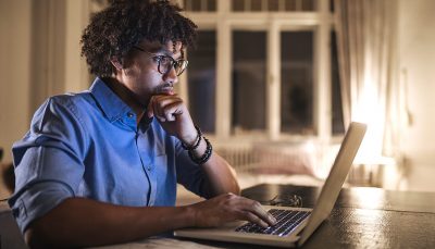 Jovem negro em sua casa trabalhando em um laptop