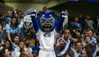 imagem de homem fantasiado de lobo azul com camisa do CIEE, animando torcida e ginásio de esportes