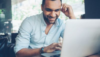 Homem sorrindo em frente ao computador