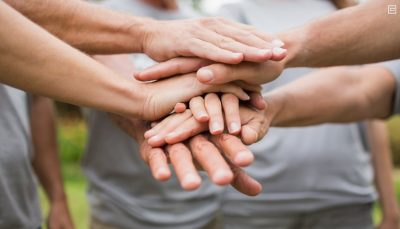pessoas em círculo unindo as mãos ao centro
