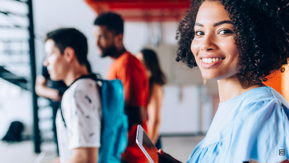 Menina com cadernos na mão está em destaque na foto sorrindo