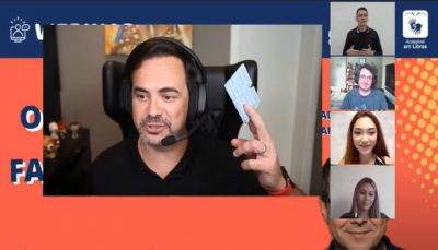 Frame do webinar, Em destaque na imagem, que reproduz a tela do computador, está o humorista Carioca com sua carteirinha do CIEE na mão. Em destaaques menores, à direita da tela, estão os demais participantes e interpréte de Libras