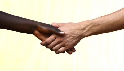 Aperto de mãos entre uma pessoa negra e uma branca